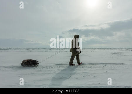 Femme avec un traîneau à pied est sur la glace du lac Baïkal. Banque D'Images