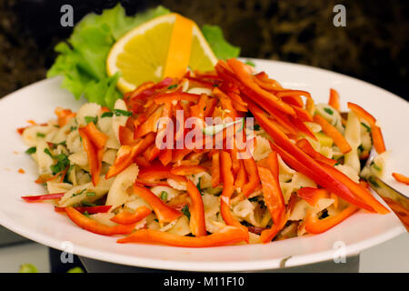 Salade de pâtes aux poivrons rouges, décorées avec le citron et feuilles de laitue Banque D'Images