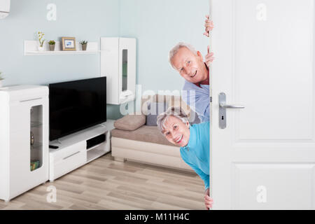 Portrait Of Smiling Senior Couple Peeking de porte Banque D'Images