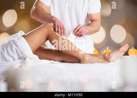 Close-up d'un thérapeute l'Épilation Femme jambe du client avec la bande de cire Banque D'Images