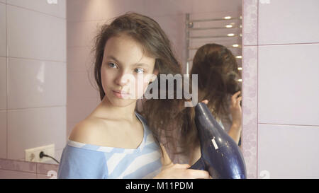 Belle teen girl sèche cheveux sèche-cheveux dans la salle de bains Banque D'Images