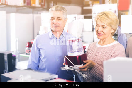 L'homme et la femme 47-57 ans sont l'achat en boutique d'électroménager et de l'extracteur de jus broyeur pour elle-même à la maison. Banque D'Images