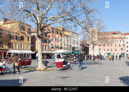 Campo Santa Margherita, Dorsoduro, Venise, Vénétie, Italie à l'heure du midi en hiver. Populaire auprès des habitants et les étudiants, les gens mangent sur des bancs et Banque D'Images