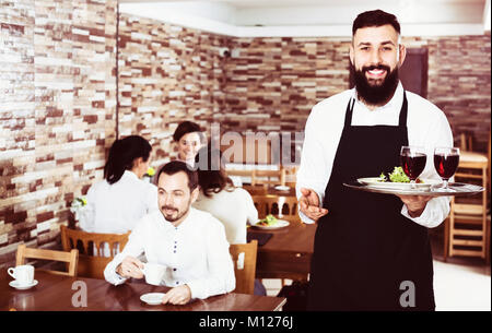 Waiter positif montrant country restaurant aux visiteurs Banque D'Images