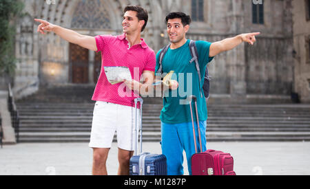 Deux amis touristes avec des valises sont à pied avec guide et carte-livre dans la rue à Barcelone. Banque D'Images