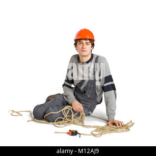 Un jeune travailleur dans l'uniforme gris attaché avec une corde blanche sur fond isolé. Banque D'Images