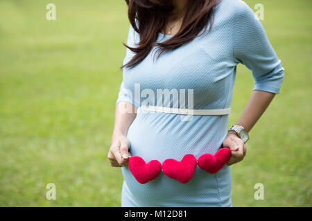 Un portrait d'une femme enceinte asiatique robe bleue en forme de coeur de portefeuille accessoires Banque D'Images