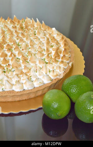 La moitié une tarte au citron avec meringue sur haut et quelques citrons Banque D'Images