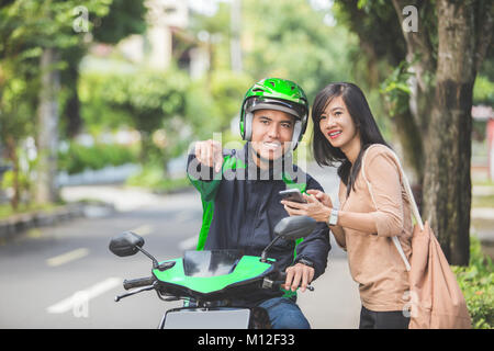 Happy young woman standing on parle de trottoir et la commande de taxi moto Banque D'Images