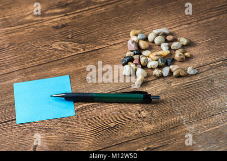 Crayon placé sur des post-it avec beaucoup de cailloux en fond de bois Banque D'Images