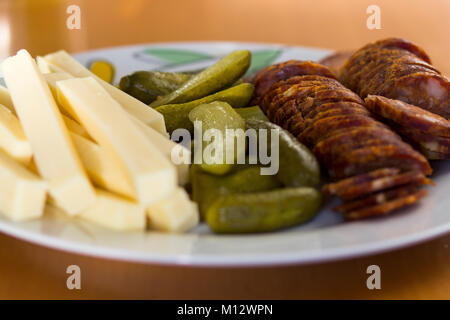 Assiette de tranches de fromage, cornichon ou concombre et cornichons saucisse épicée dans un angle faible vue rapprochée Banque D'Images