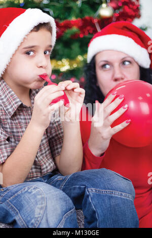 Mère Fils pour gonfler des ballons à Noël Banque D'Images