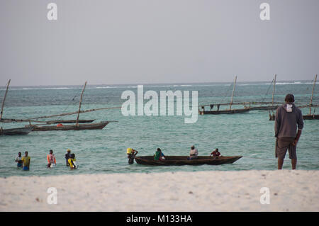 Un Swahaili Montres homme les pêcheurs aller en mer pour pêcher sur la plage de Nungwi, Zanzibar, avec de l'eau turquoise et vert de l'Océan Indien Banque D'Images