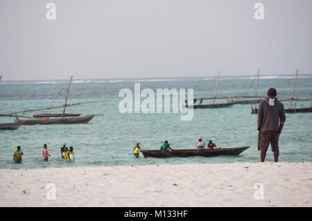 Un Swahaili Montres homme les pêcheurs aller en mer pour pêcher sur la plage de Nungwi, Zanzibar, avec de l'eau turquoise et vert de l'Océan Indien Banque D'Images