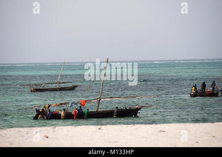 Aller en mer des pêcheurs en bateaux dhow traditionnel à Nungwi sur l'île de Zanzibar et ses eaux turquoises de l'Océan Indien Banque D'Images
