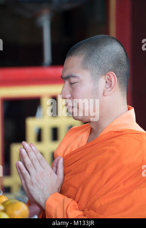 Un moine bouddhiste prie dans un temple à Bangkok, Thaïlande Banque D'Images