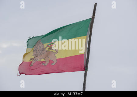 Légèrement déchiré Ethiopian Lion de Juda dans la brise soufflant du pavillon avec un fond de ciel bleu Banque D'Images