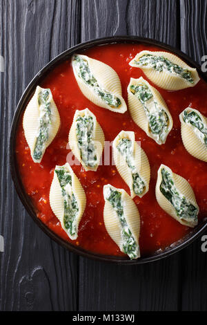 De délicieuses pâtes conchiglioni farci aux épinards et ricotta, sauce tomate gros plan sur une assiette. Haut Vertical Vue de dessus Banque D'Images