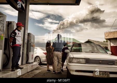 Bicol, Philippines. 25 janvier, 2018. Une famille regarde la erruption du volcan Mayon en remplissant leur voiture avec l'essence. Credit : Lewis Inman/Alamy Live News Banque D'Images