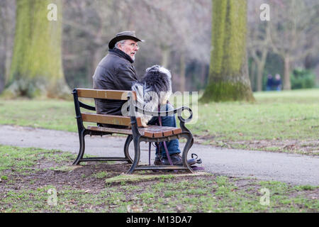 Northampton. Météo Royaume-uni, Abington park. 26 janvier 2018. Un homme est assis sur un des bancs de parc avec son petit chien noir et blanc dans la région de Abington Park cet après-midi. Un après-midi froid gris avec un peu de soleil prévu pour plus tard. Credit : Keith J Smith./Alamy Live News Banque D'Images