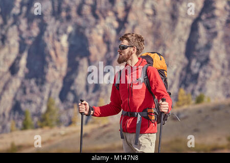 Tall backpacker avec barbe et lunettes de tenir dans la main. poteaux Printemps ensoleillé l'aube dans les montagnes rocheuses. Sac à dos de randonneur avec position sur rocky view point Banque D'Images