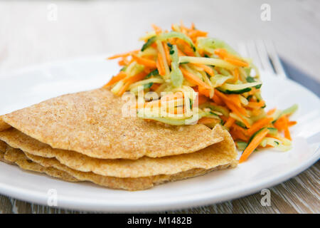 Crêpe de seigle complet avec salade de légumes - végétalien sain, nourriture végétarienne, pas de recette d'oeufs. Gros plan sur la plaque blanche, plat réel. Crêpe tout-en-un Banque D'Images