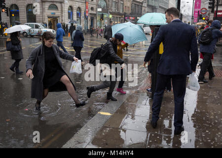 Londres, le 24 janvier 2018 : Tempête Georgina ont balayé certaines parties de l'Angleterre et au centre de Londres, l'heure du déjeuner des employés de bureau ont été capturés par des pluies torrentielles et des vents violents. Les piétons ont eu recours à l'ensemble des flaques bondissant à la jonction de New Oxford Street et de Kingsway à Holborn. Crédit : Richard Baker / Alamy Live News. Banque D'Images