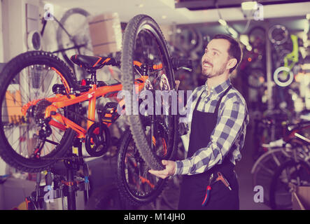 Working Man définit la roue sur le vélo dans un magasin d'articles de sport Banque D'Images