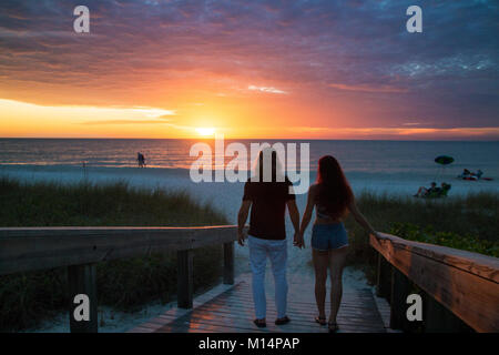 Beautiful couple in love silhouettes se tenant la main et marcher sur la plage de sable exotiques romantique coucher de soleil, plage et jetée de Naples, Florida, USA Banque D'Images