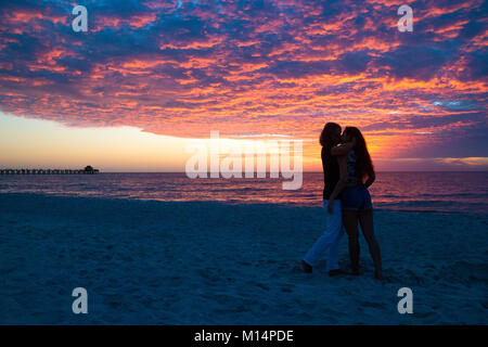 Silhouette couple romantique embrasser passionnément sur Paradise beach tout en soleil colorés crépuscule, Naples Pier beach, la ville de Naples, Floride USA Banque D'Images