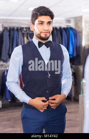 L'homme est d'essayer sur l'image choisie devant le miroir dans la boutique. Banque D'Images