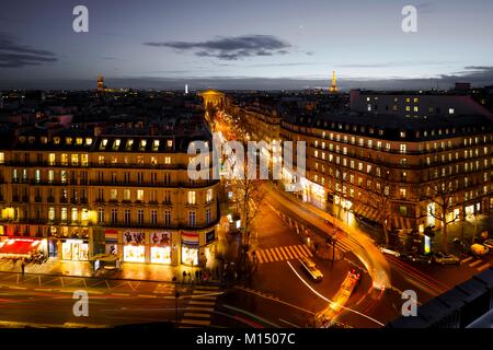 Scène de rue de l'antenne à Paris, France la nuit illuminée avec des bâtiments historiques, magasins et une artère animée avec légèreté de traf mobile Banque D'Images