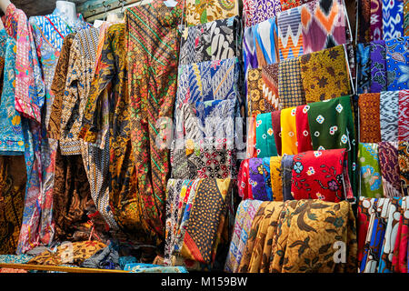 Sélection de vêtements batik coloré affiché à l'extérieur d'un atelier de batik sur la rue Malioboro. Yogyakarta, Java, Indonésie. Banque D'Images