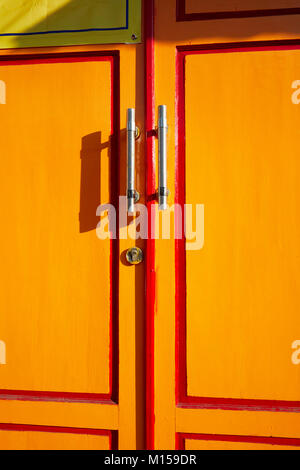 Fragment de porte en bois peint jaune avec poignées en métal. Yogyakarta, Java, Indonésie. Banque D'Images