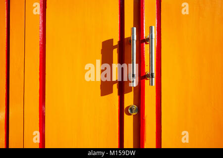 Fragment de porte en bois peint jaune avec poignées en métal. Yogyakarta, Java, Indonésie. Banque D'Images