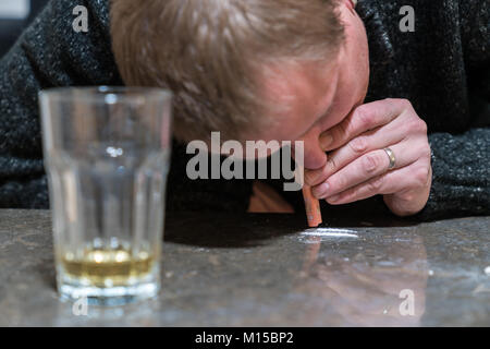 L'homme est d'essence poudre de cocaïne à billet sur une table Banque D'Images