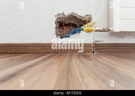 Trou dans le mur intérieur et tuyaux de chauffage Banque D'Images