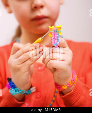 Bracelet bijoux fille tisse la gomme à mâcher, tissage, passe-temps sur un fond clair Banque D'Images