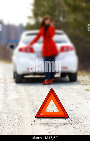Femme debout par la rupture de la voiture et le triangle de signer Banque D'Images