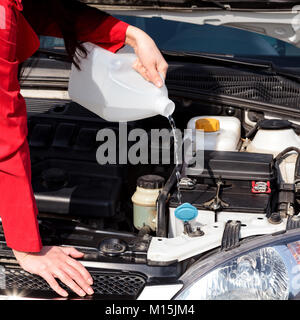 Portrait of woman pouring liquide lave-glace en voiture Banque D'Images