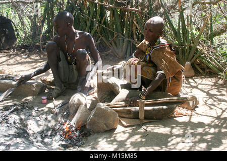 Homme de Datoga prépare et allume le feu de camp à l'aide d'une peau de chèvre d'un soufflet. Photographié en Afrique du Sud, la Tanzanie, le lac Eyasi Banque D'Images