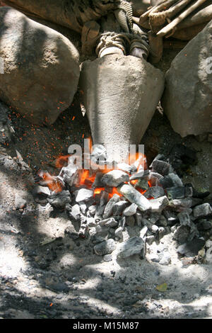 Homme de Datoga prépare et allume le feu de camp à l'aide d'une peau de chèvre d'un soufflet. Photographié en Afrique du Sud, la Tanzanie, le lac Eyasi Banque D'Images