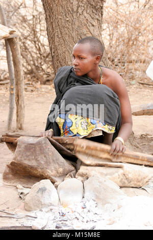 Homme de Datoga prépare et allume le feu de camp à l'aide d'une peau de chèvre d'un soufflet. Photographié en Afrique du Sud, la Tanzanie, le lac Eyasi Banque D'Images