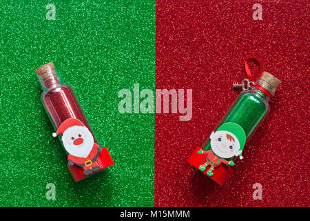 Pot tube pot de paillettes de Noël - rouge avec le Père Noël le sur et vert avec Elf sur - sur red & green glitter feuille de mousse texture background Banque D'Images