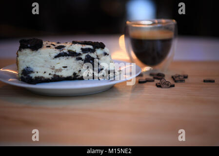 La nourriture faite maison de biscuit chocolat cheesecake avec un coeur d'amour et de l'éclairage décorations avec une boisson chaude au café expresso en arrière-plan Banque D'Images