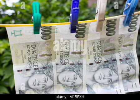 Pinces à linge colorées couronnes tchèque tenir sur une corde. Dans l'arrière-plan sont des arbustes. Banque D'Images