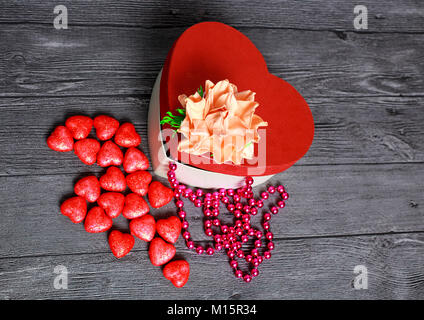 Ajar boîte rouge en forme de coeur. Sur la couverture fort et fleur décorative, il y a des perles. Suivant sur la table est un tas de coeurs Banque D'Images