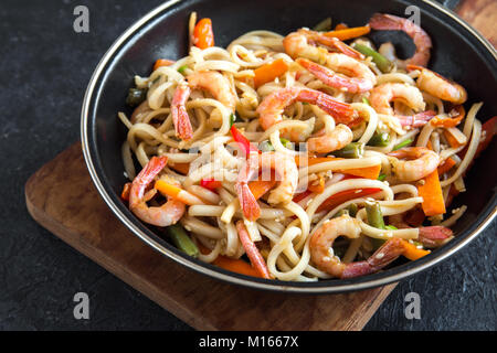 Faire revenir avec les nouilles Udon, crevettes (crevettes) et de légumes. La nourriture saine, de l'Asie, repas sautés au wok sur fond noir, copiez l'espace. Banque D'Images