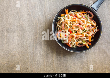 Faire revenir avec les nouilles Udon, crevettes (crevettes) et de légumes. La nourriture saine, de l'Asie, repas sautés au wok sur fond de bois, copie de l'espace. Banque D'Images