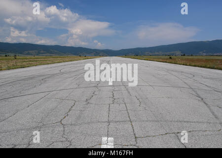 Piste abandonnée utilisé comme piste de rallye. Chaude journée d'été. Les fissures et les traces de pneus de voiture vu sur la surface asphaltée Banque D'Images